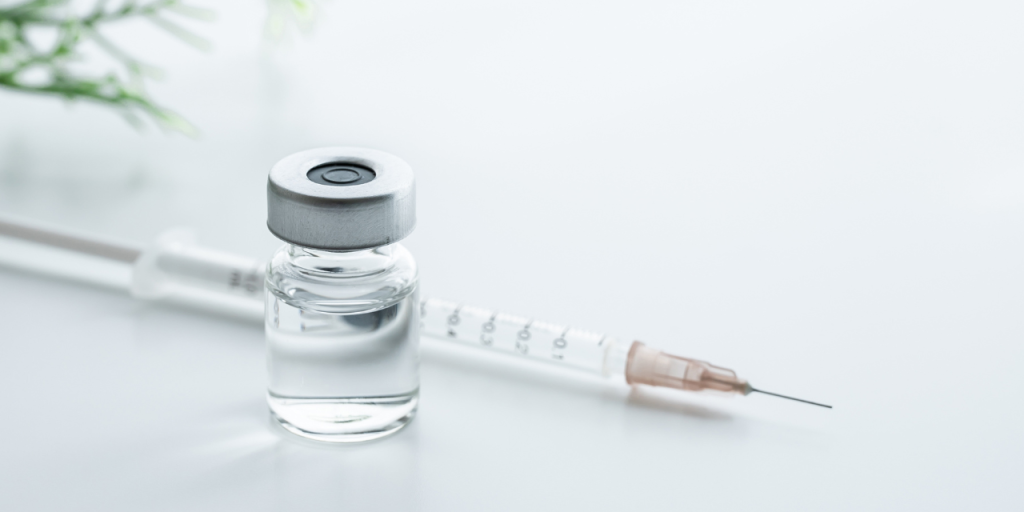 A syringe laying on a table next to a vial of medicine.