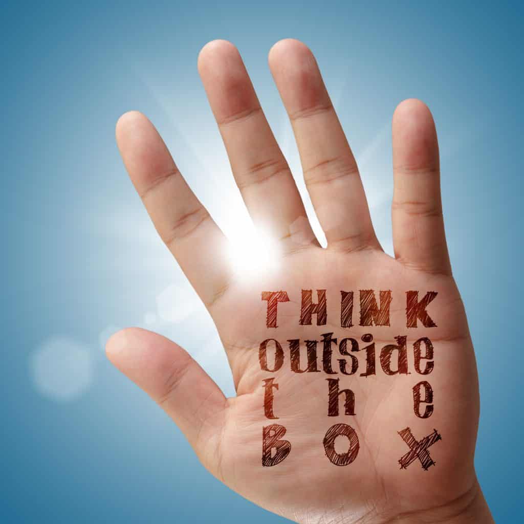 Hand with "think outside the box" written on it