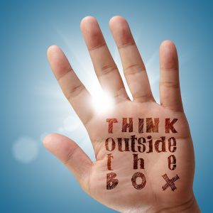 Hand with "think outside the box" written on it
