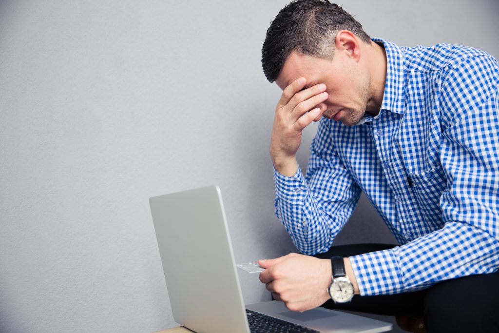 Person rubbing eyes while holding a credit card