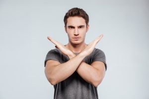Person standing with arms crossed over chest in an "x'