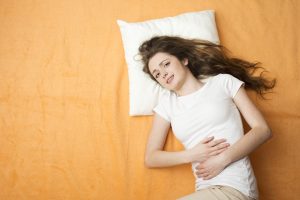 Person laying down holding their stomach