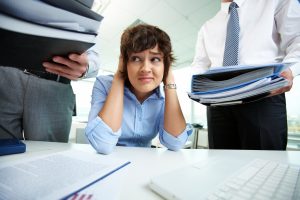 Person holding their head while others stand above them carrying binders