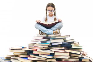 Kid sitting on a pile of books reading