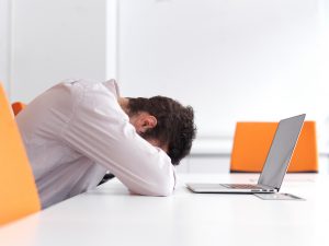 Person sitting with head resting on desk