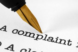 Tip of ink pen above the word "complaint"