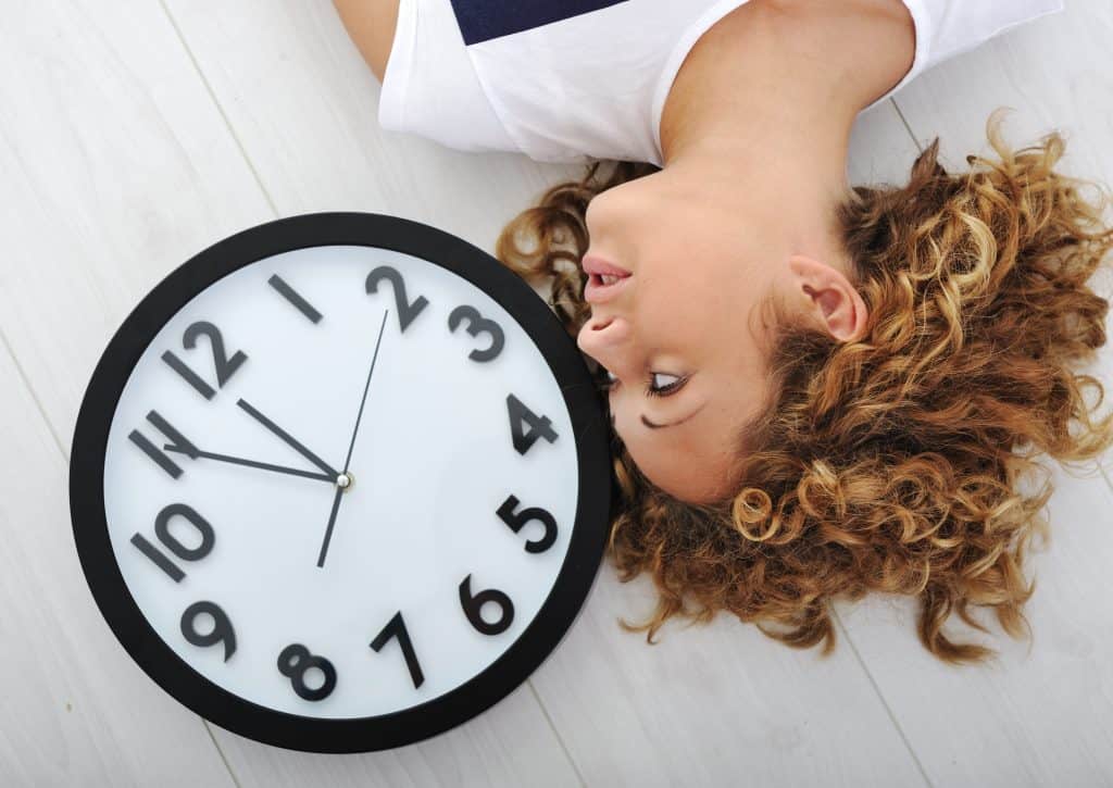 Person laying next to a clock