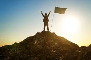 Person standing ontop of a hill next to a flag