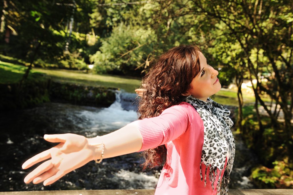Person standing outside with arms spread wide
