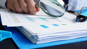 Person reviewing documents with a magnifying glass
