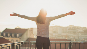 Person standing on a balcany with arms outstretched