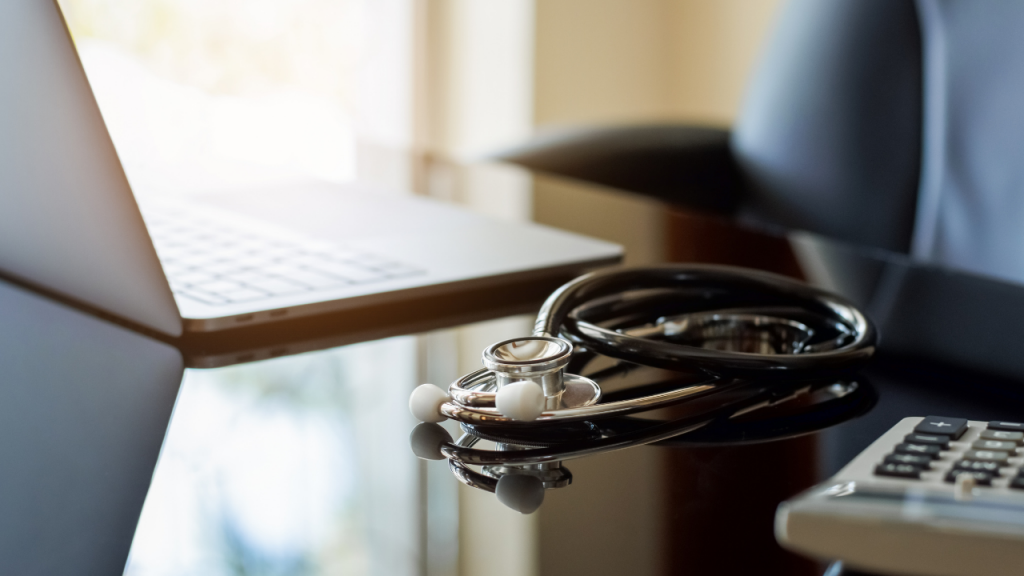 Stethoscope laying between a computer and a calculator