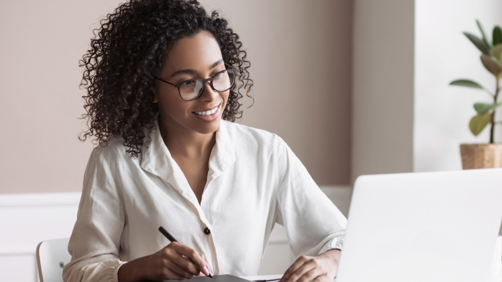 Professional taking notes while using a computer.