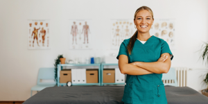 Chiropractic physician leaning against table.