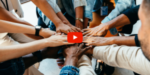 People standing in a circle with their hands stacked in the middle